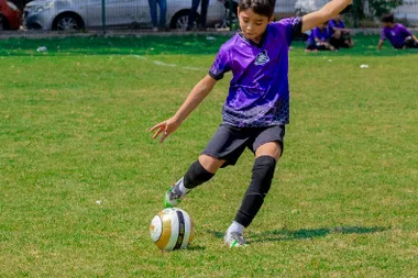 Jóvenes futbolistas jugando un partido competitivo en cancha grande